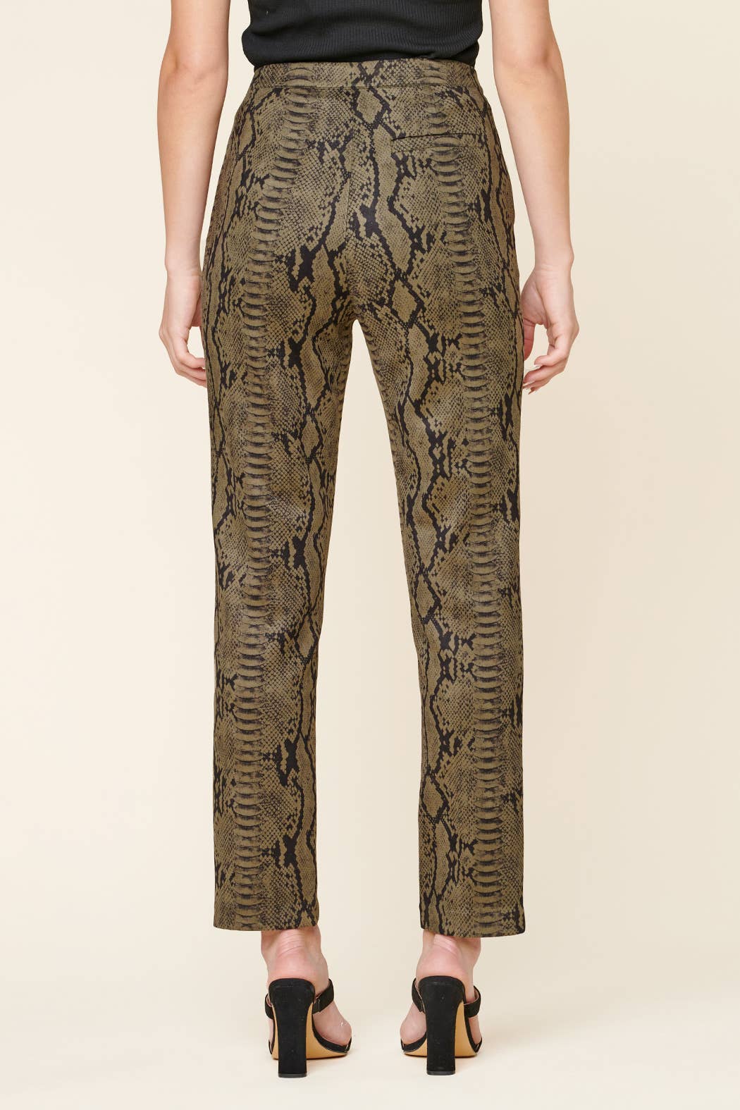 Snakeskin patterned pants worn by a person on a beige background