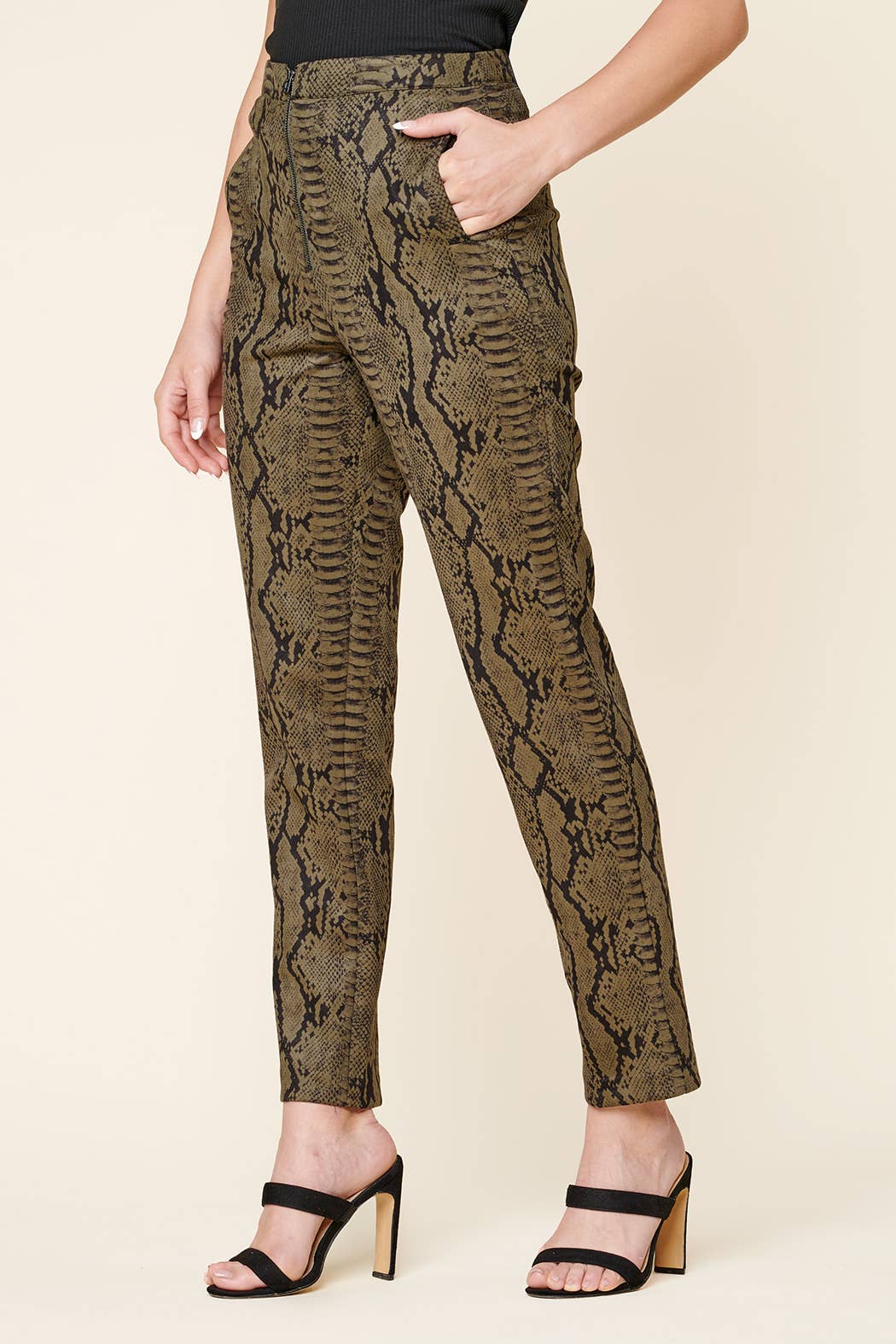 Snakeskin patterned pants worn by a person on a beige background