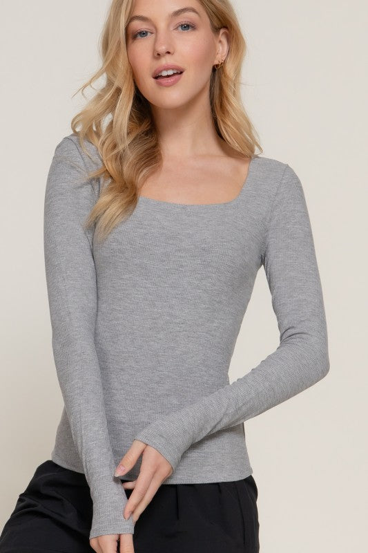 Woman wearing a gray long-sleeve top against a plain background