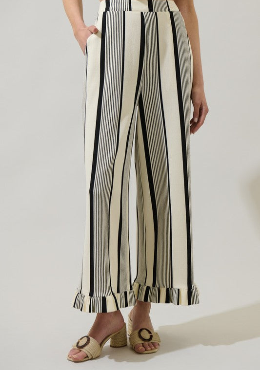 Person wearing black and white striped pants on a plain background