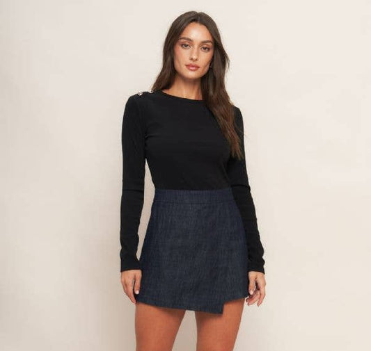 Woman wearing a black top and dark denim skirt with black knee-high boots on a white background