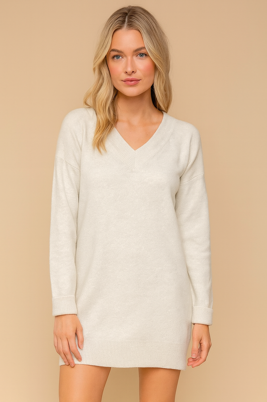 Woman wearing a gray sweater dress against a beige background