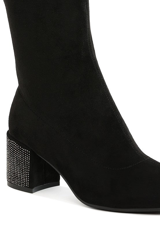 Black knee-high boot with a studded block heel on a white background