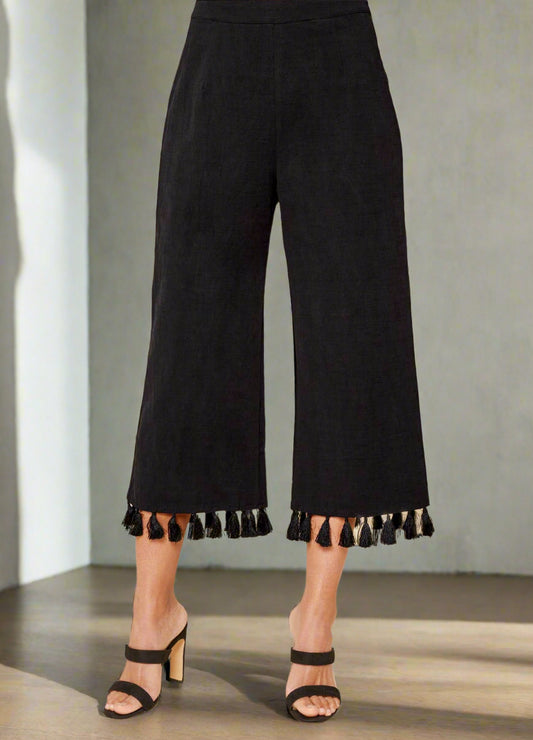 Black tasseled pants worn by a person on a beige background