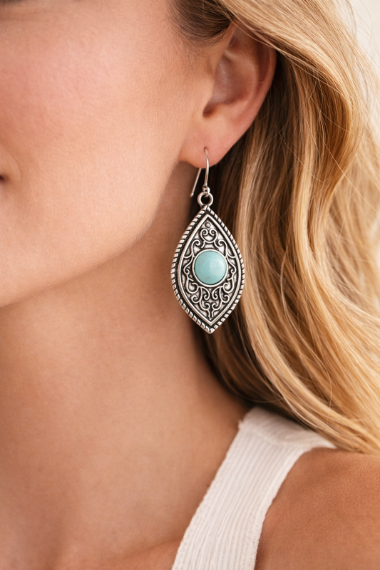 Close-up of a woman wearing a silver earring with a turquoise stone.