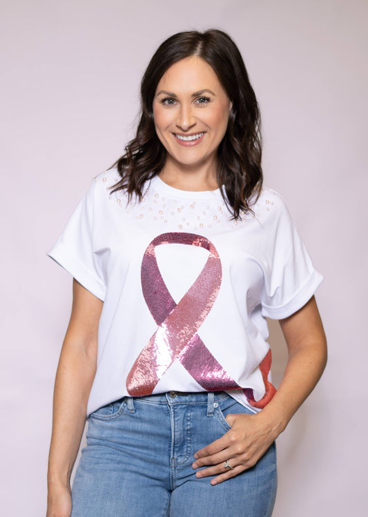 Woman wearing a white t-shirt with a pink and red ribbon design on a plain background