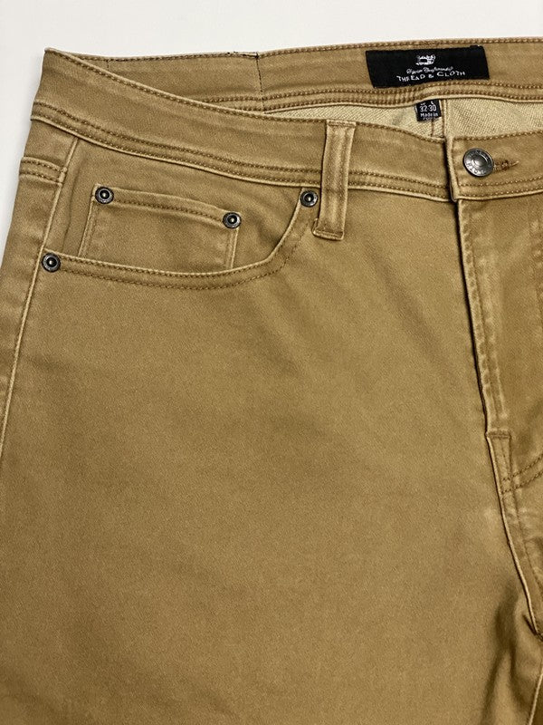 Close-up of brown pants with a brand label on a white background