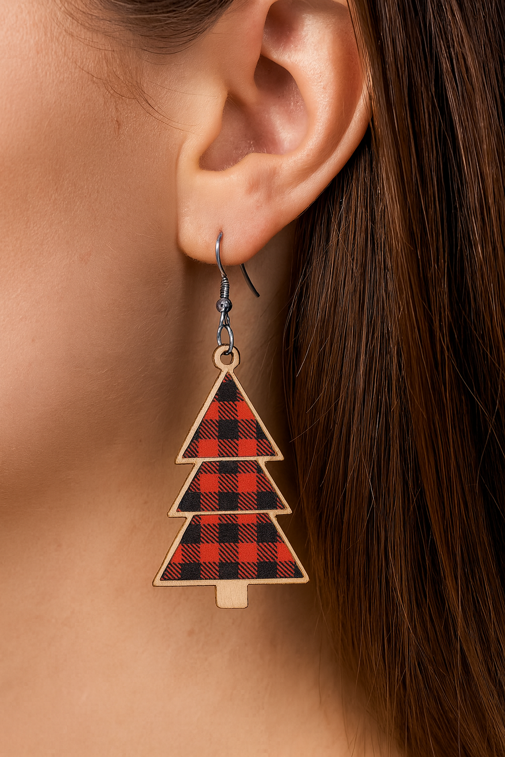 Plaid triangle-shaped earring worn by a person with brown hair.