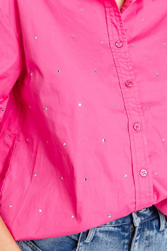 Close-up of a bright pink shirt with rhinestone embellishments on a white background