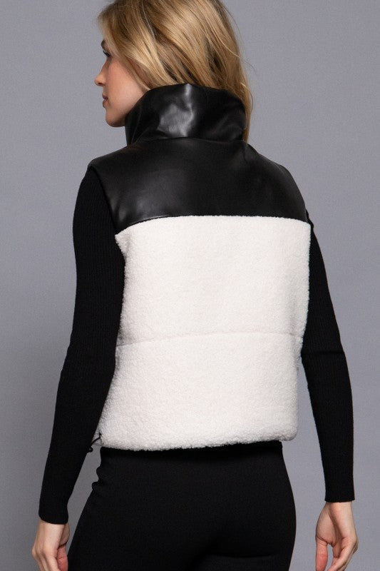 Person wearing a black and white vest with a gray background