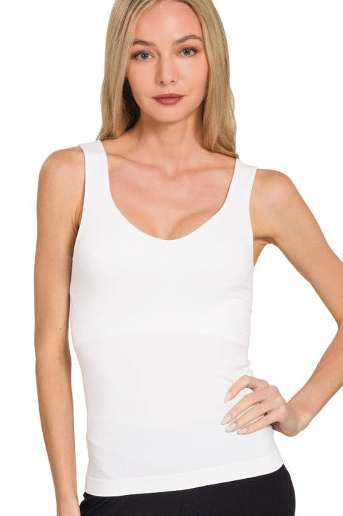 Woman wearing a white tank top against a plain background