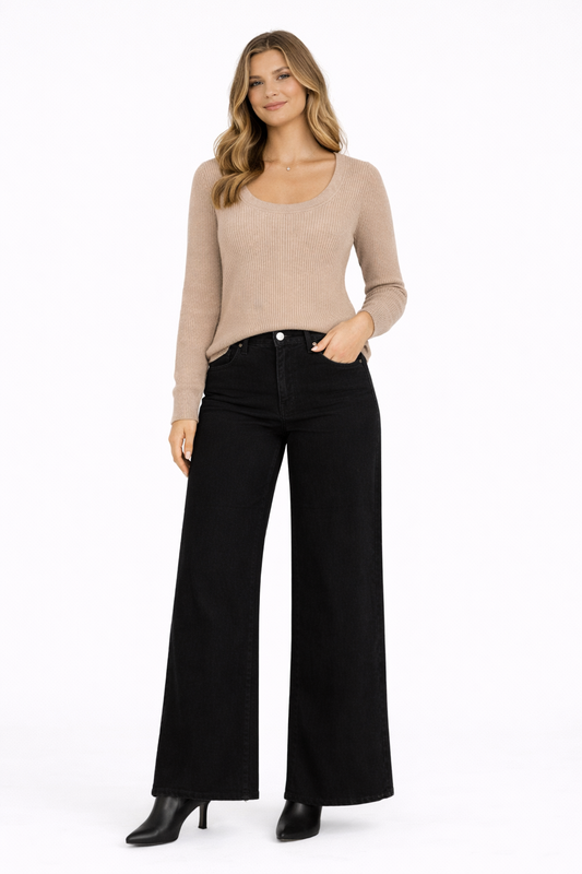 Woman wearing a beige sweater and black wide-leg jeans on a white background