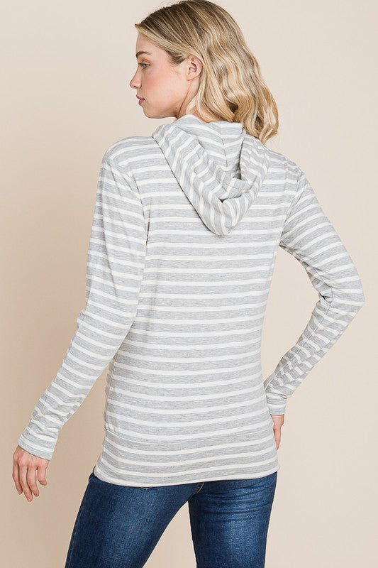 Woman wearing a gray and white striped hoodie on a beige background