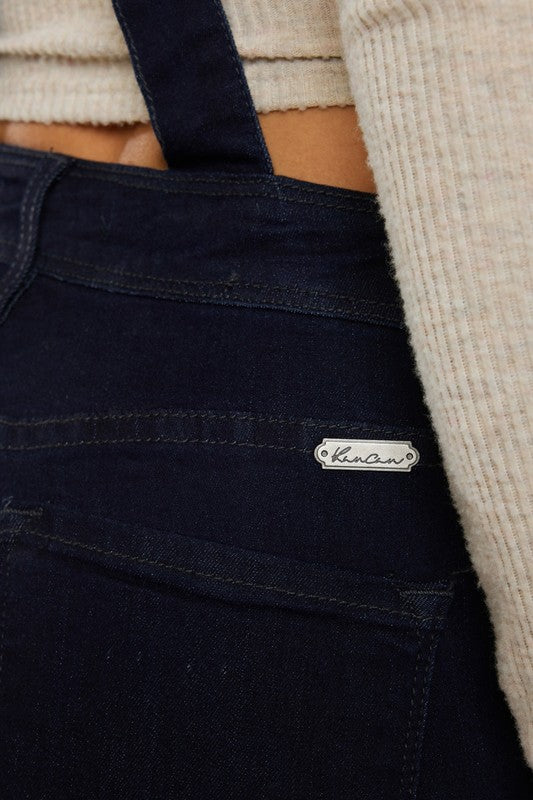 denim overalls with a brand label on the pocket against a neutral background