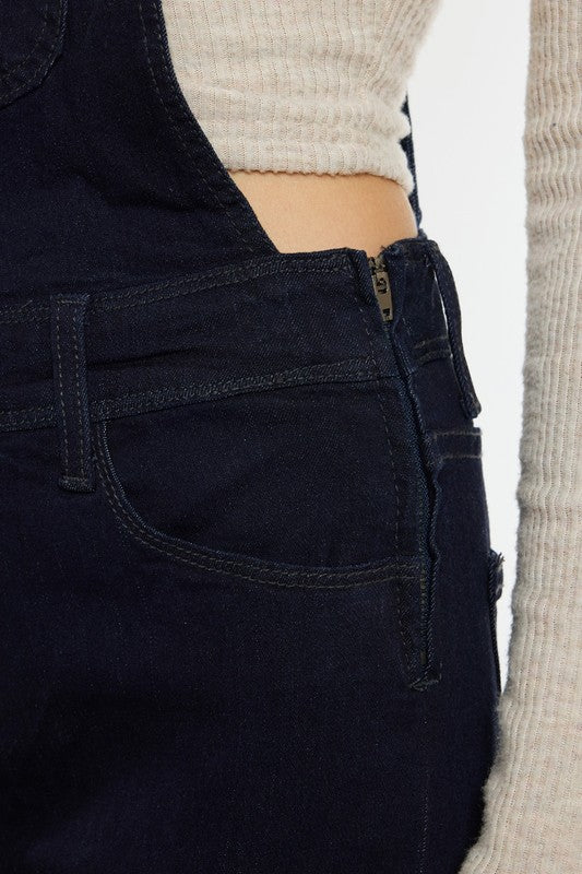 denim overalls worn by a person with a neutral background
