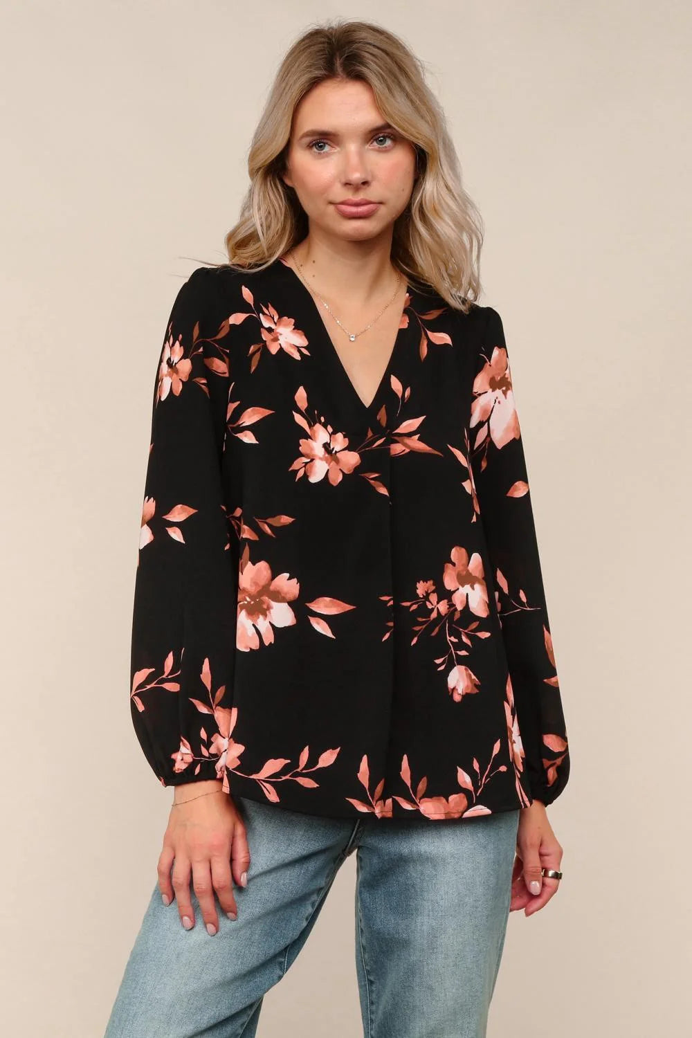 Woman wearing a black floral long-sleeve top against a beige background