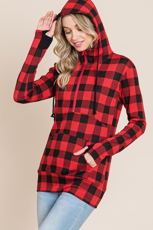 Woman wearing a red and black plaid hoodie on a beige background