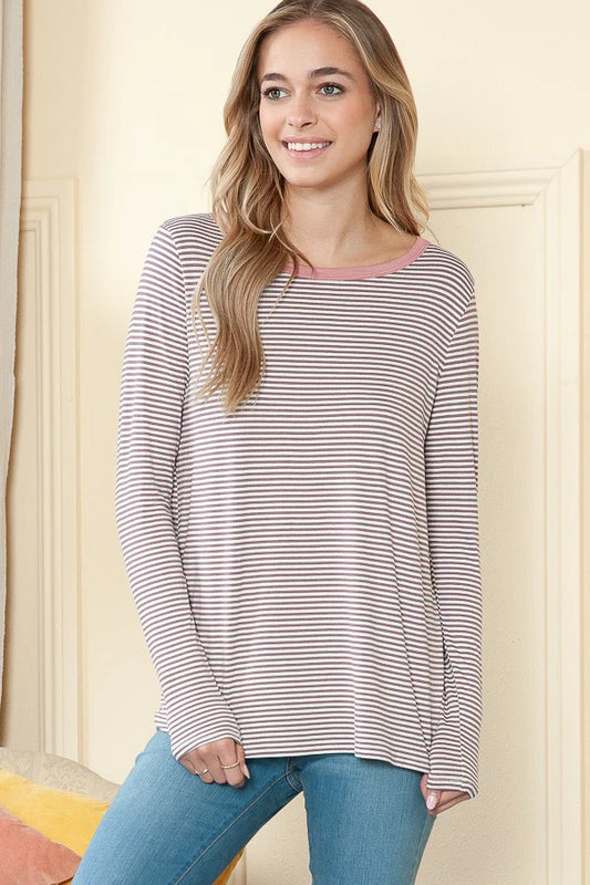 Woman wearing a striped long-sleeve top and jeans against a neutral background