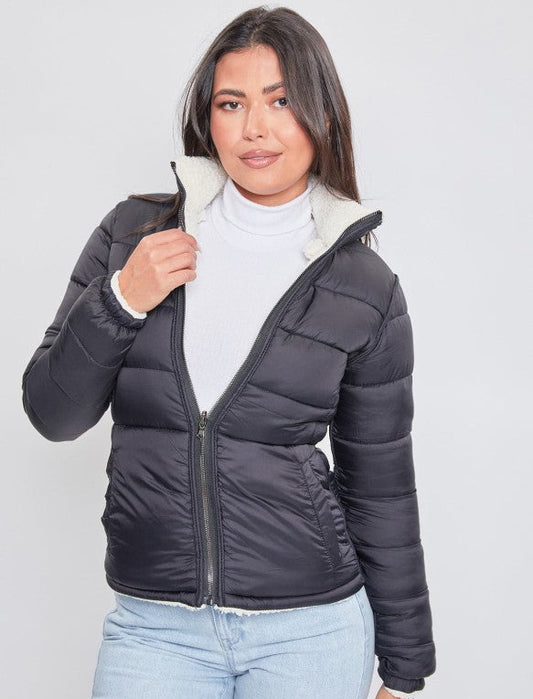 Woman wearing a black puffer jacket with a white interior on a plain background