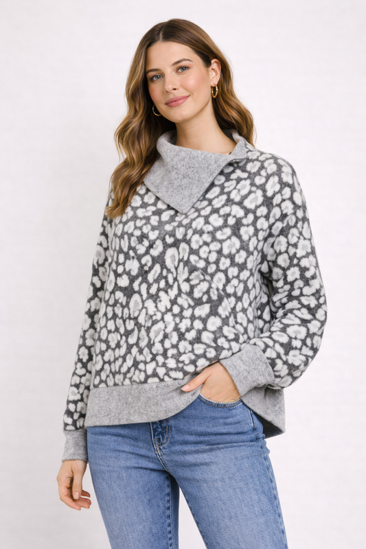 Woman wearing a gray and white patterned sweater with blue jeans on a white background