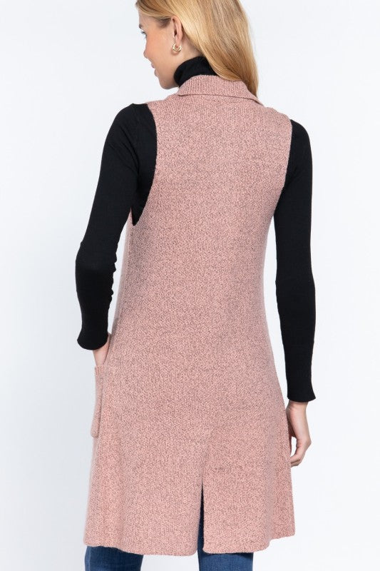 Woman wearing a pink vest over a black long-sleeve shirt on a white background