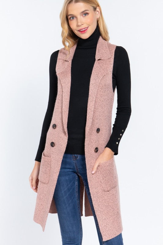 Woman wearing a long pink vest over a black turtleneck and blue jeans on a white background