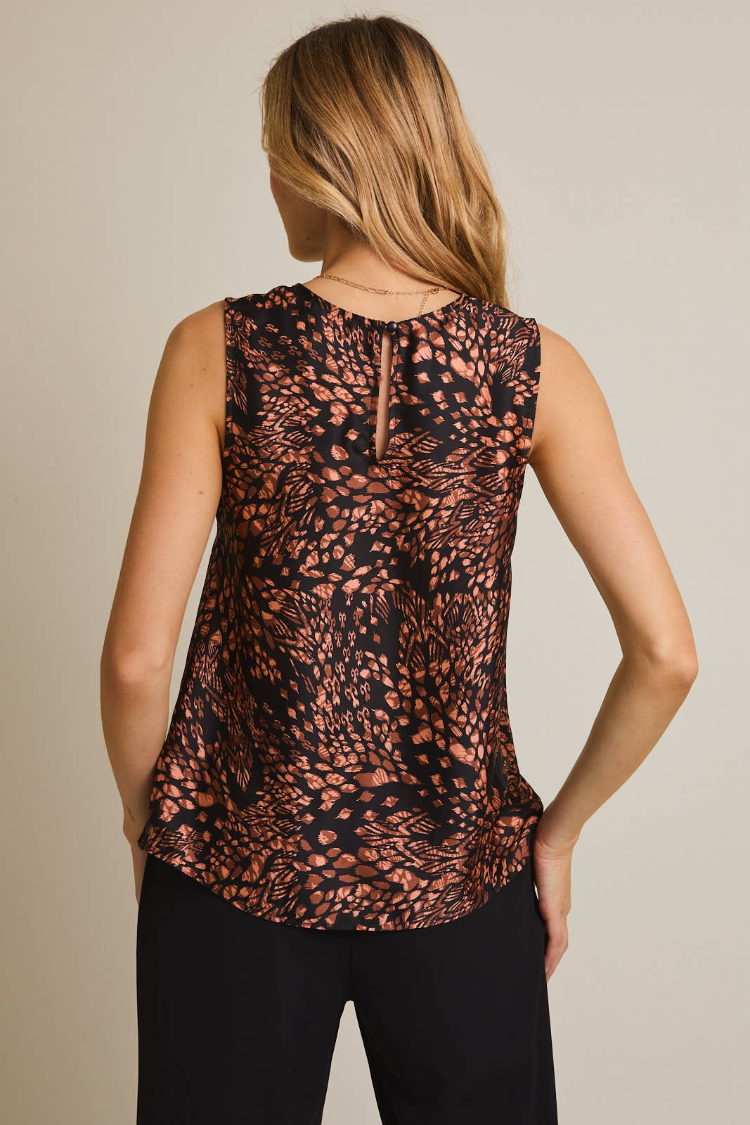 Woman wearing a sleeveless top with a pattern on a plain background
