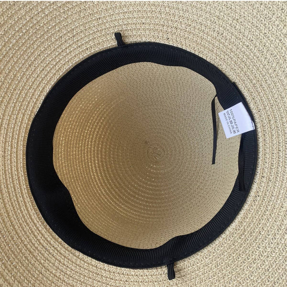 Beige straw hat with black band and tag on a beige background