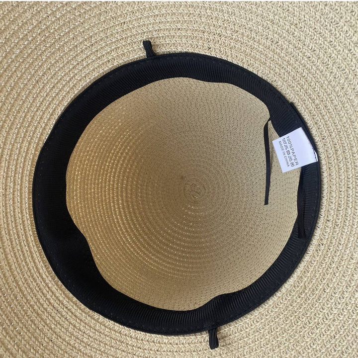 Beige straw hat with black band and tag on a beige background