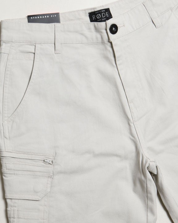 Close-up of light gray pants with a brand label on a white background