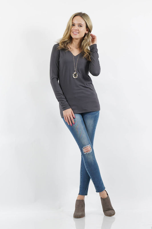 Woman wearing a gray long-sleeve top and blue jeans on a white background