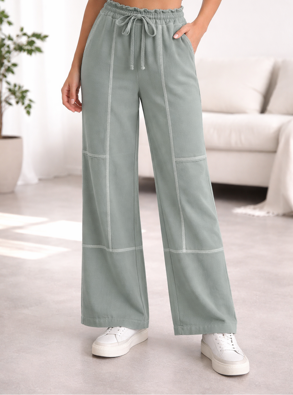 Person wearing light ash jade wide-leg pants in a living room setting