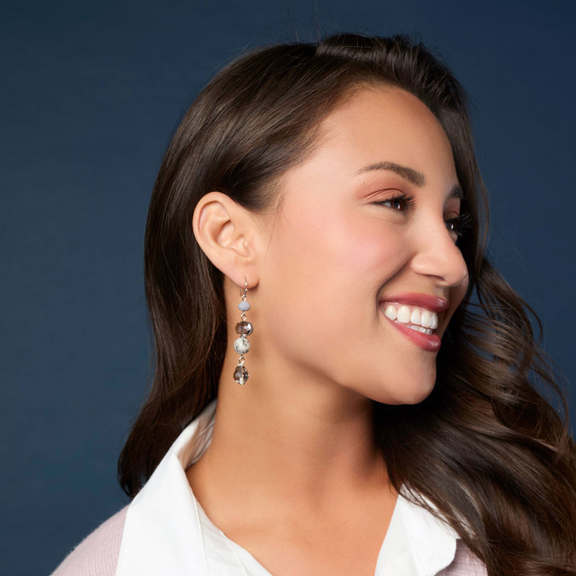 Woman wearing earrings with a silver background