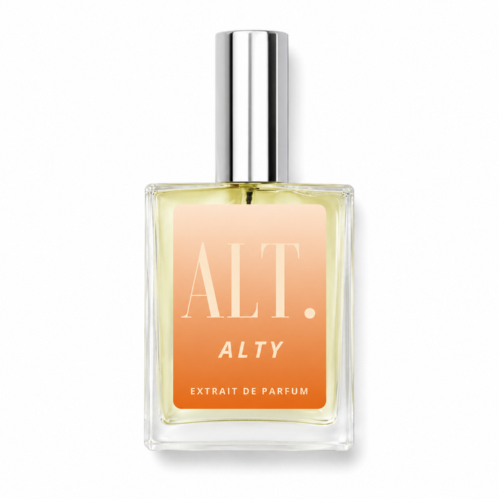 A rectangular glass perfume bottle with a silver cap, filled with a pale yellow liquid and featuring a peach-to-orange gradient label with the text &