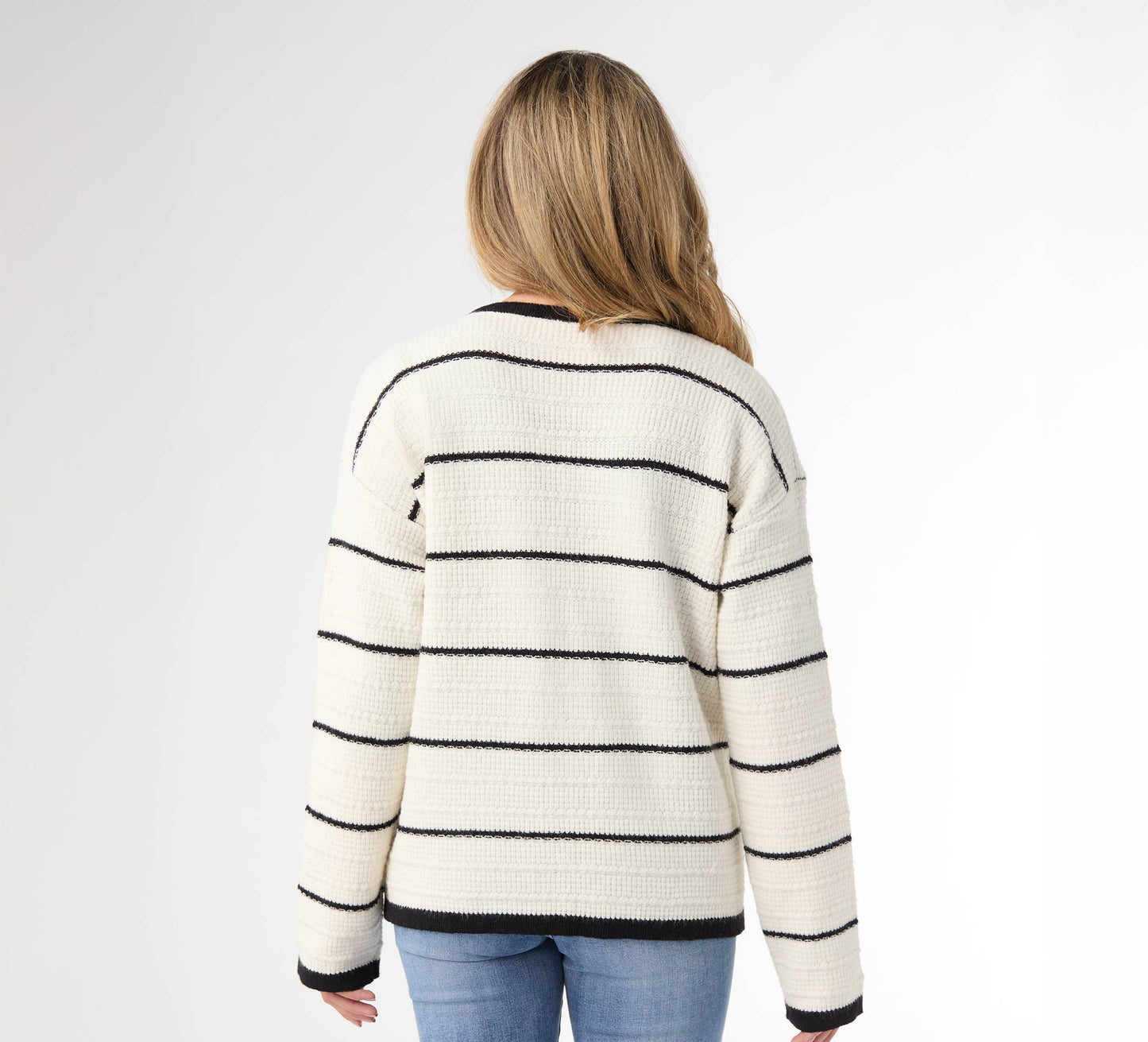 Person wearing a striped sweater and blue jeans on a white background