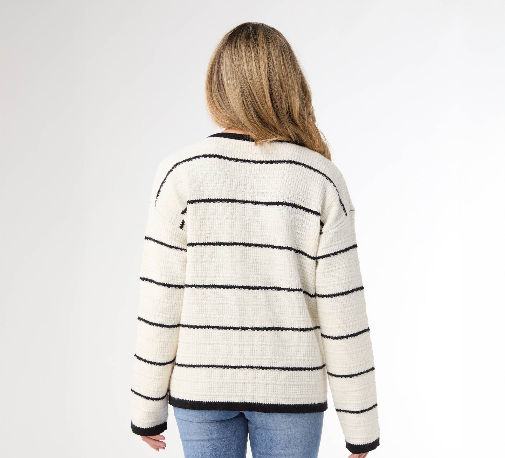 Person wearing a striped sweater and blue jeans on a white background