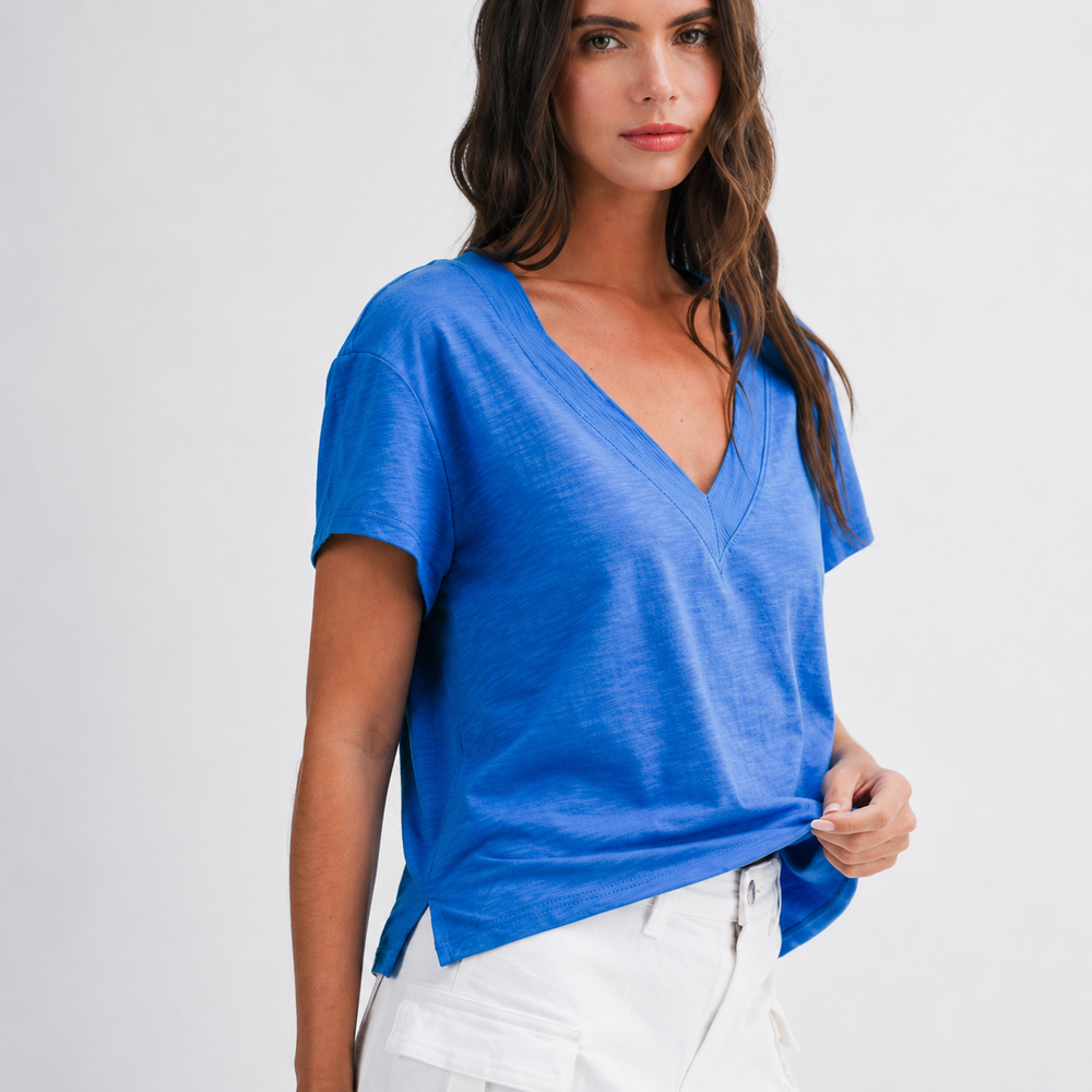 Woman wearing a blue top and white pants on a plain background