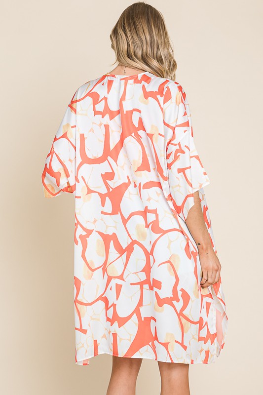 Woman wearing a white dress with orange floral pattern on a beige background