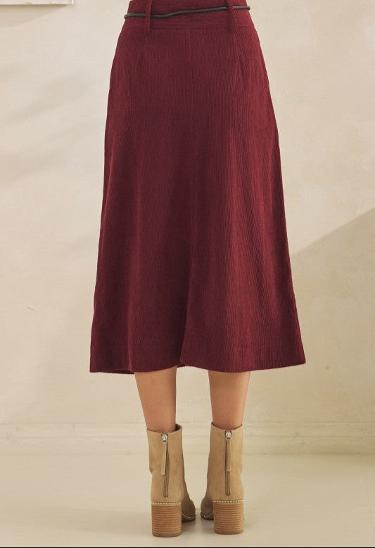 Maroon skirt worn by a person on a beige background
