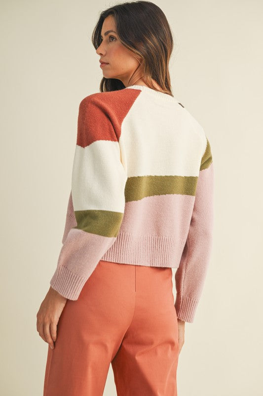 Woman wearing a colorful sweater with pink, white, and gold stripes on a beige background