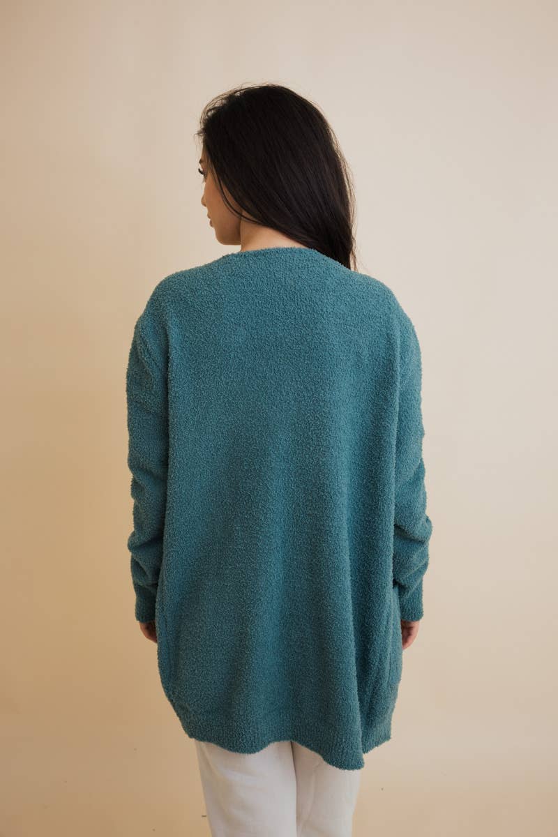 Person wearing a teal sweater against a beige background