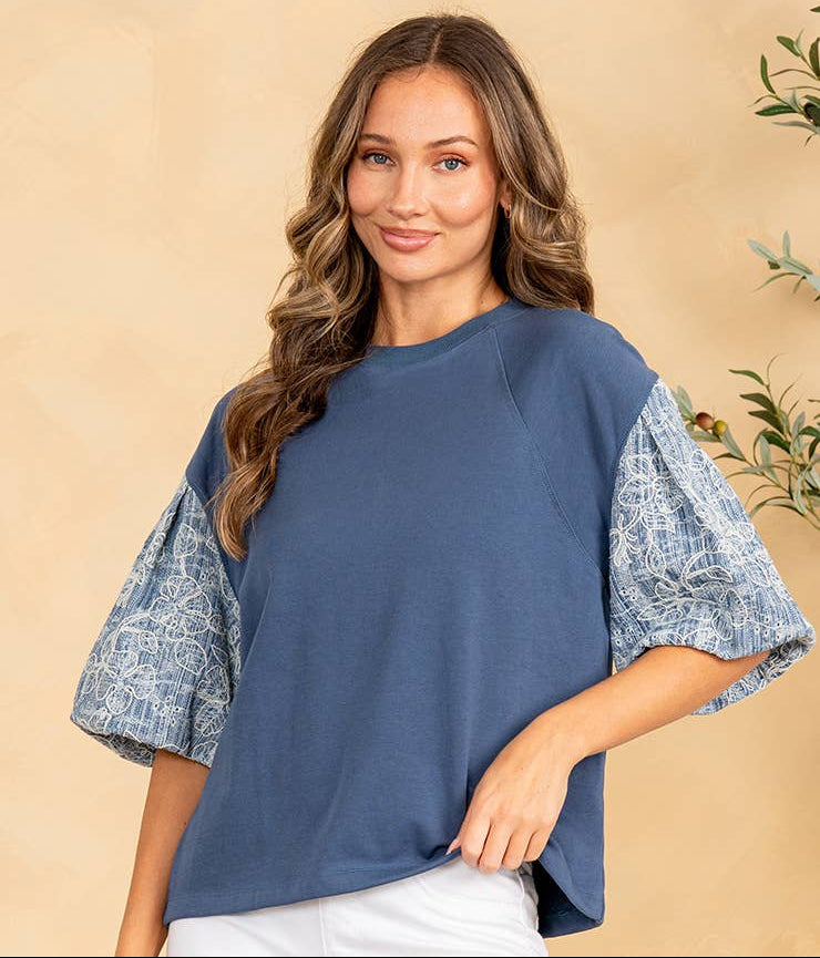 Woman wearing a blue top with patterned sleeves against a beige background