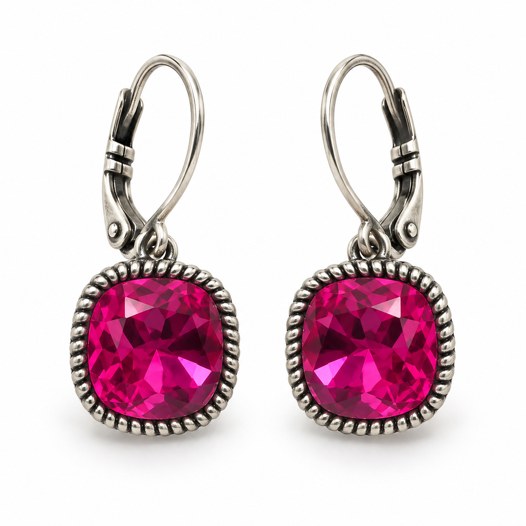 A pair of silver leverback drop earrings featuring large, round, faceted hot pink gemstones in a textured silver bezel setting, shown on a plain white background.