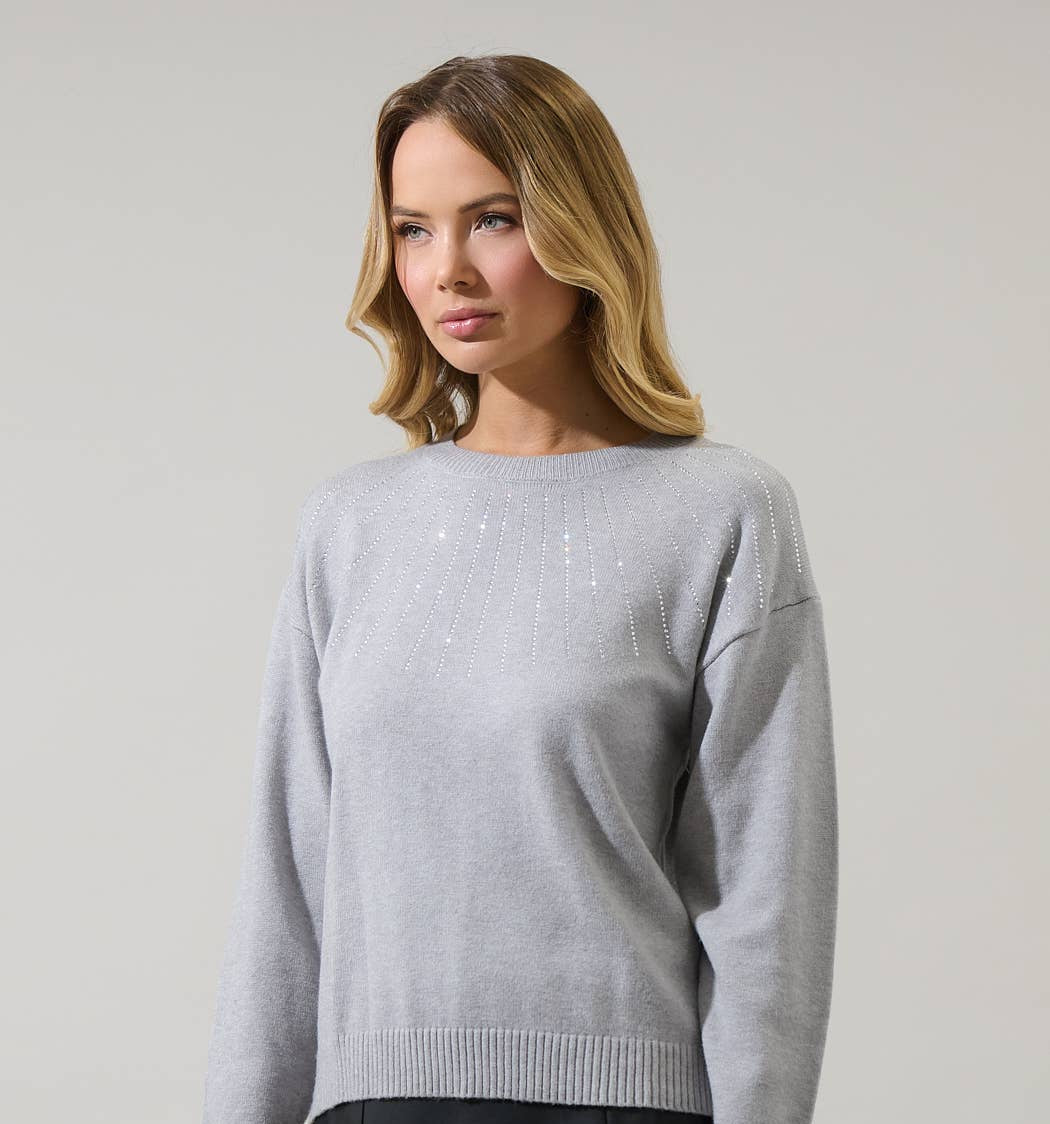 Woman wearing a gray sweater and black skirt against a plain background