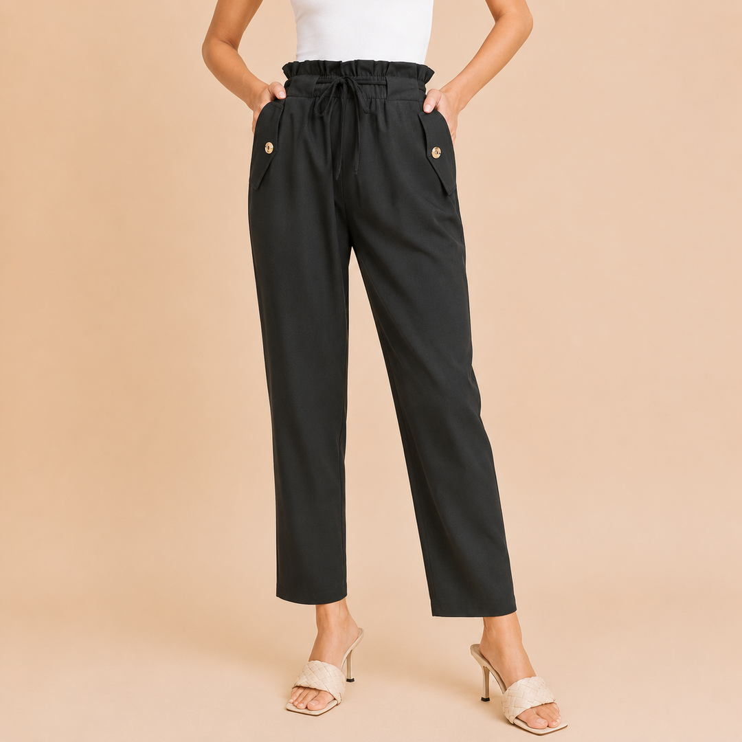 Black pants with button details worn by a person on a beige background