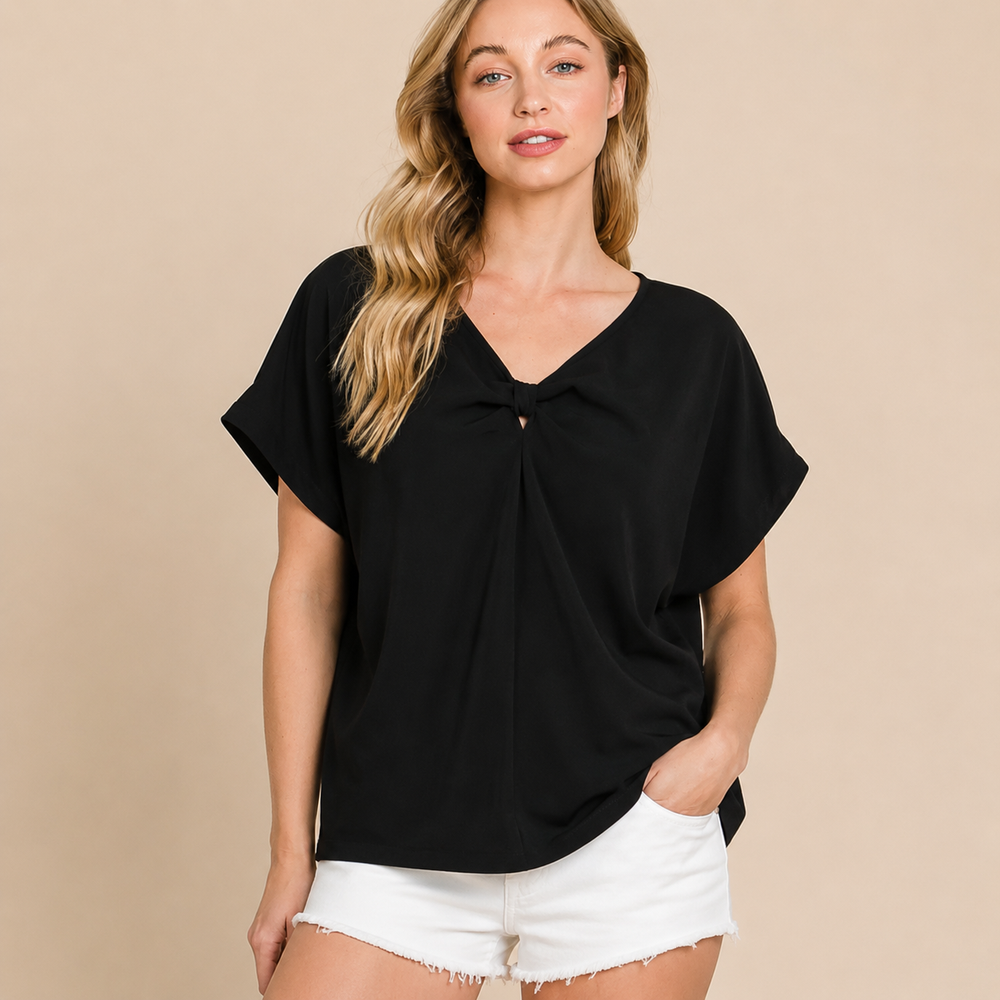 Woman wearing a black top and white shorts on a beige background