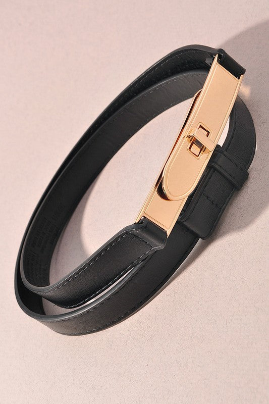 Black leather bracelet with a gold clasp on a light beige background