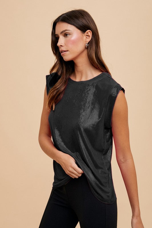 Woman wearing a black sleeveless top against a beige background