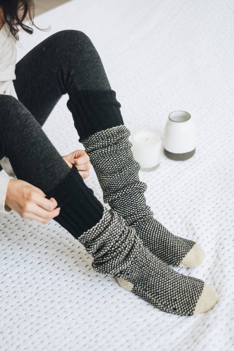 Person wearing black leggings and patterned socks on a white surface