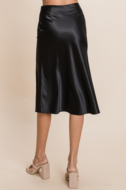 Black satin skirt worn by a person on a beige background